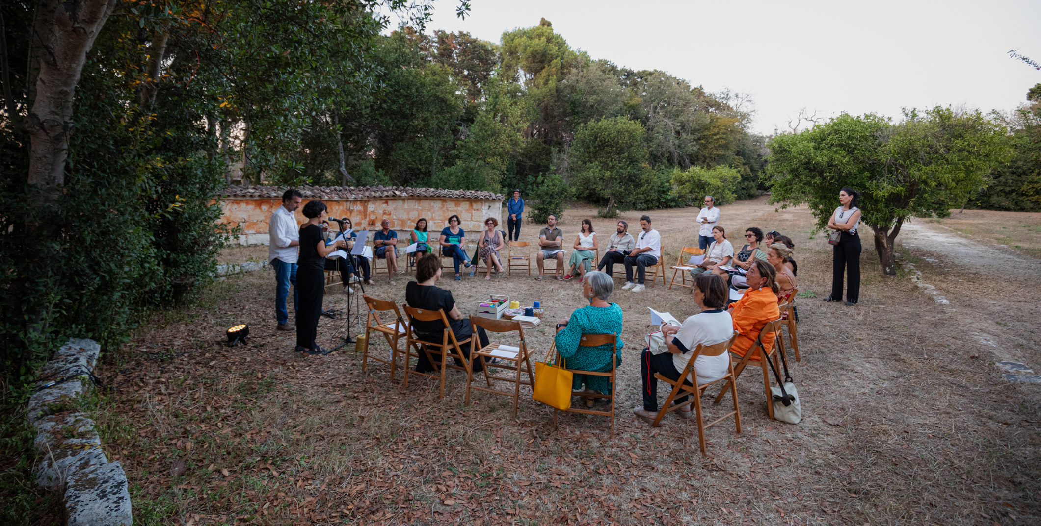 Progetto Casamassella: gruppo di persone riunite di giorno in campagna, sedute in cerchio a discutere